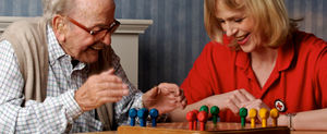 DRK-Betreuerin spielt mit einem Senioren ein Brettspiel